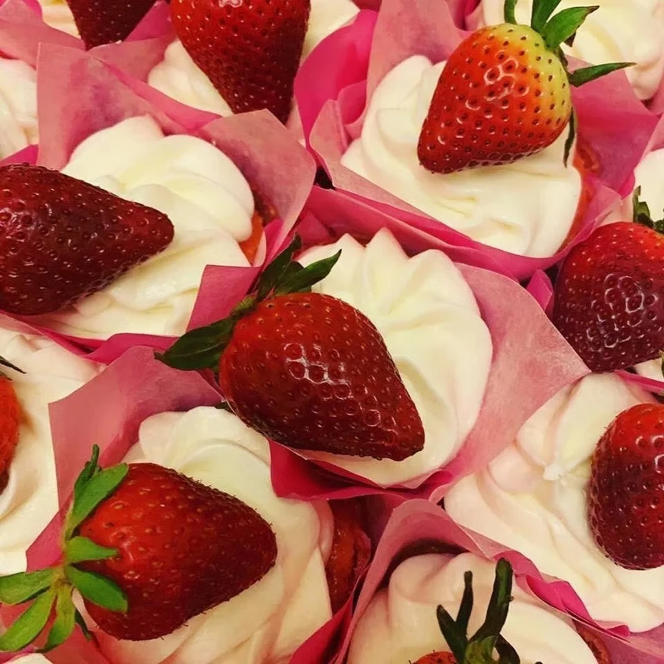 Strawberry cupcakes topped with fresh berries in pink tulip liners